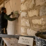 Isoler un mur en pierre avec ITI/ITE : artisan pose une isolation perspirante